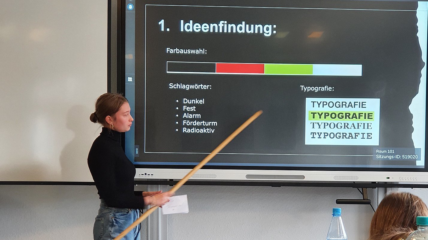 Eine Person erklärt etwas anhand einer Präsentation auf einem Bildschirm mit der Überschrift "Ideenfindung".