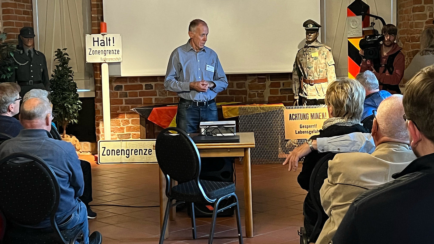 Ein Mann stellt die Ausstellung vor Publikum vor..
