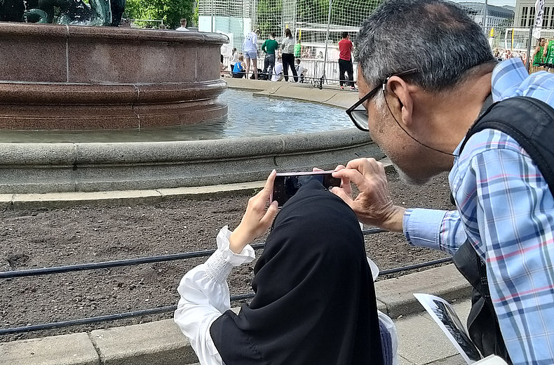 Ein Mann und ein Mädchen fotografieren einen Brunnen.