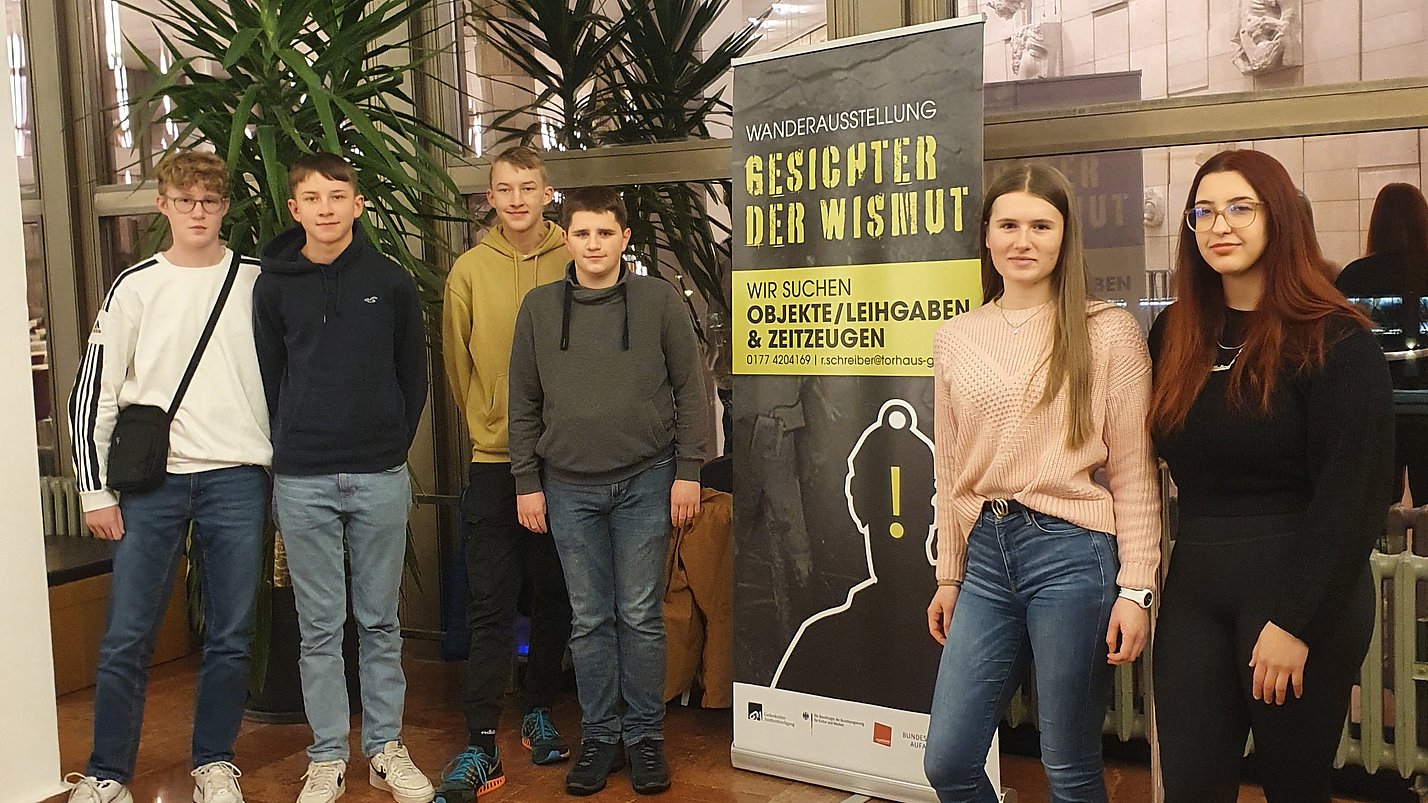Jugendliche stehen vor einem Banner des Projektes.