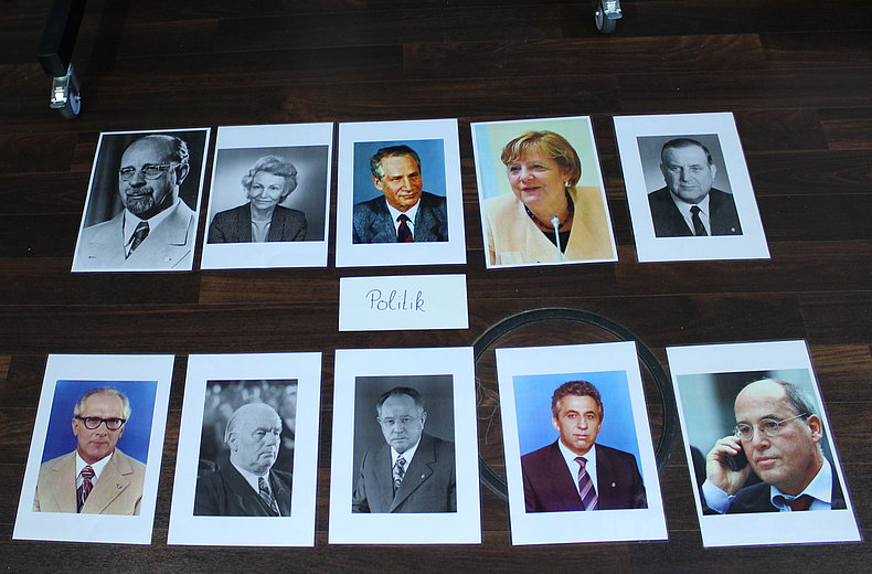 Karten mit Portraits von Politikern liegen auf dem Boden.