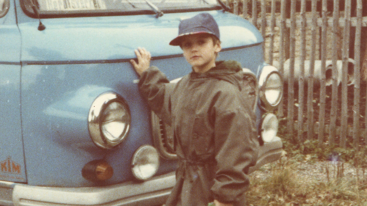 Ein älteres Foto von einem Jungen neben einem alten Bully.